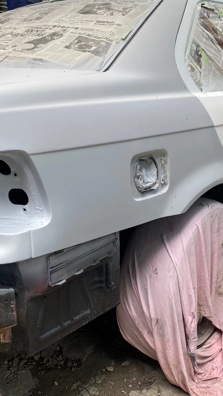 Rear quarter panel in primer with fuel filler flap, bumper removed, pink cloth