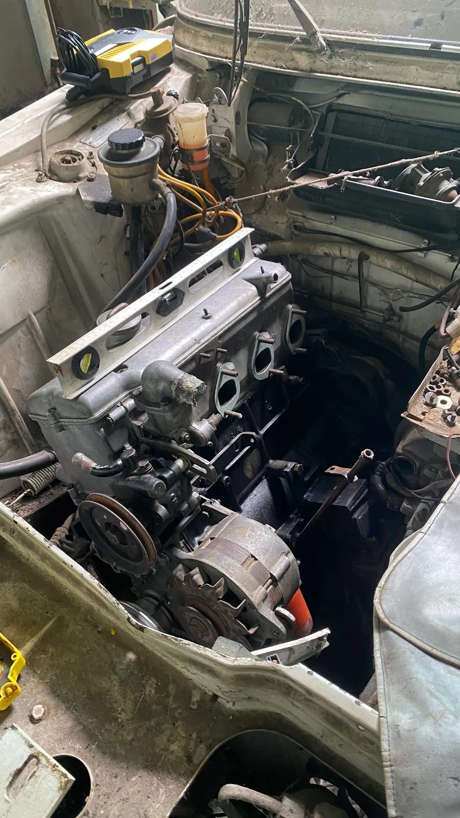 Engine bay of the old BMW saloon with a different aluminium four-cylinder engine fitted, alternator and cam cover