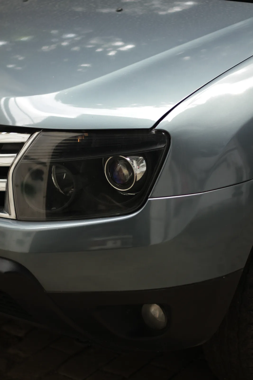 Headlight and wing of a grey Renault Duster