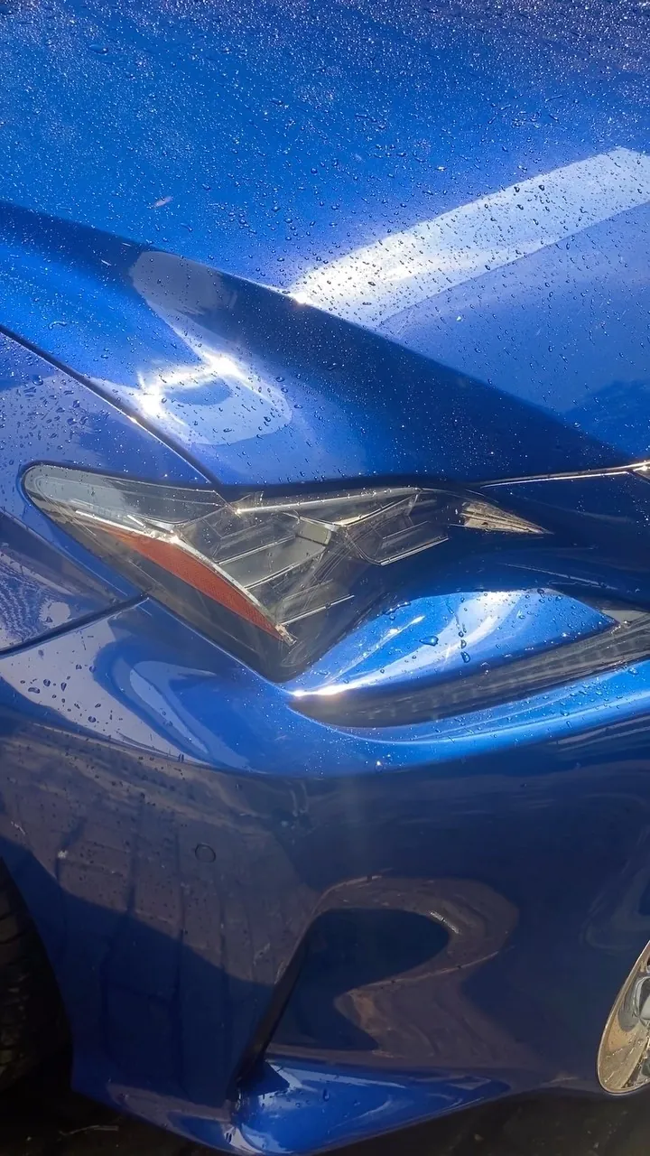Headlight and bumper of a blue Lexus RC with water beads