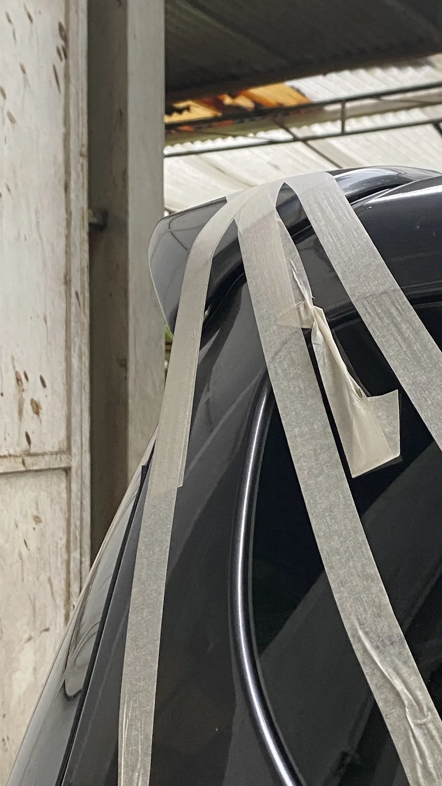 Rear spoiler on a Toyota Sienta held with masking tape while it is fitted