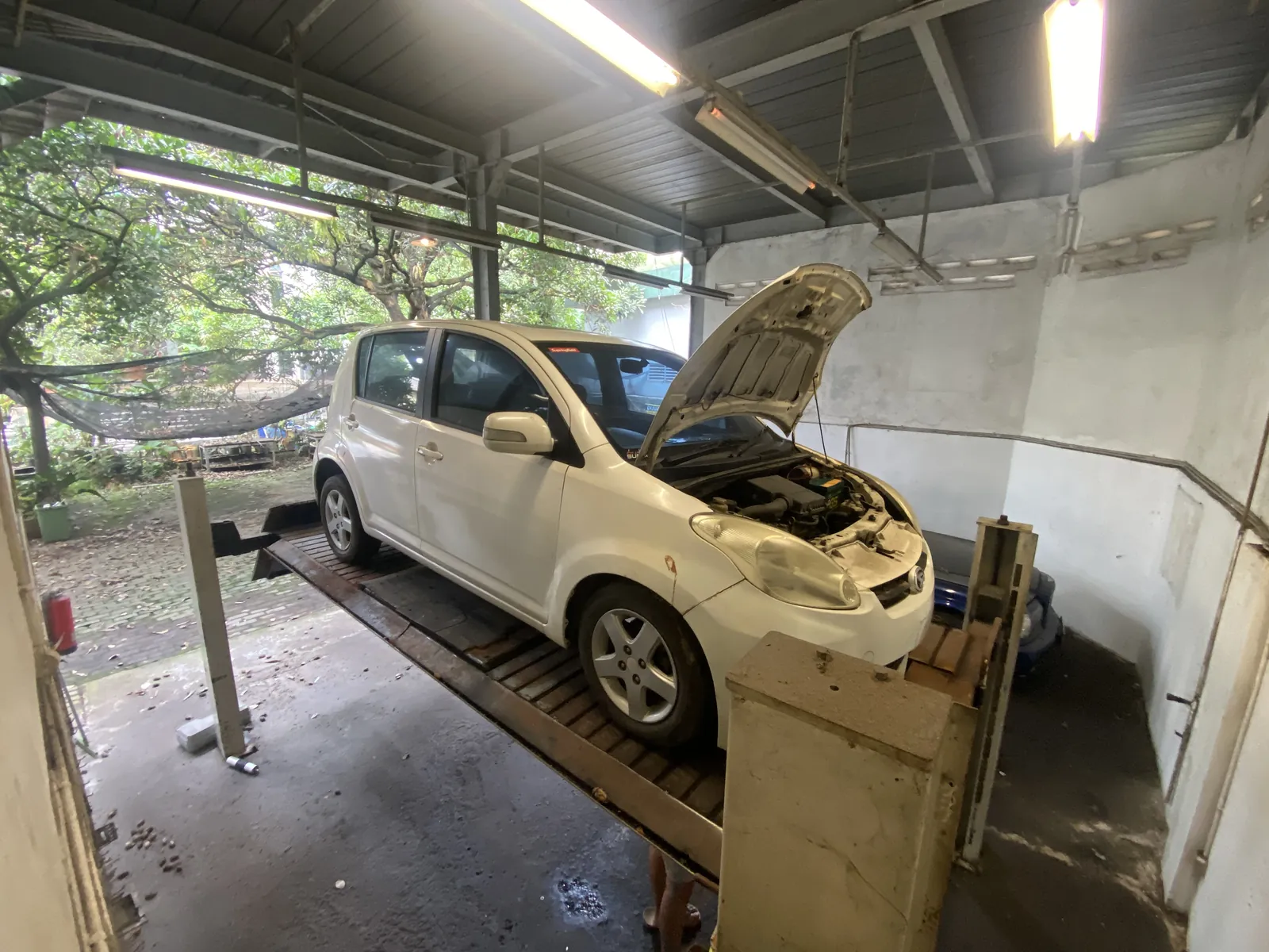 White Daihatsu Sirion on a lift with the bonnet open